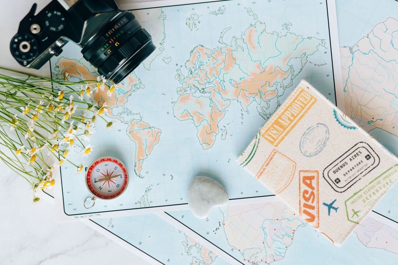 Home Flat lay of travel essentials: maps, camera, compass, and travel journal for planning adventures.