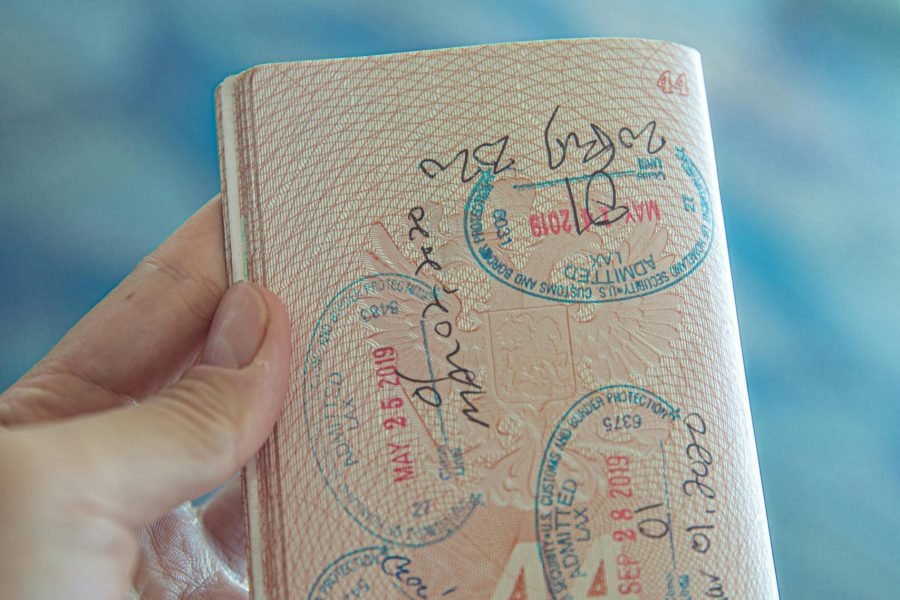 A close-up view of a hand holding an open passport with various stamps, highlighting travel experiences.